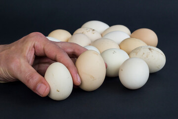 Organic,fresh large size uncooked eggs on black background with copy space.Hand holding.