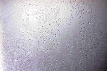 Water drops on a blurred background in close-up. Raindrops on a sunset background. Water on glass. Drops hang