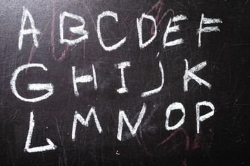 Fototapeta na wymiar School board. The board on which the alphabet is written, numbers, an example of addition. Wipe the board with a rag. Fingers of a hand in chalk from a school board