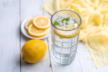 Cold Detox Water with lemon slices and mint on a white wood table 
