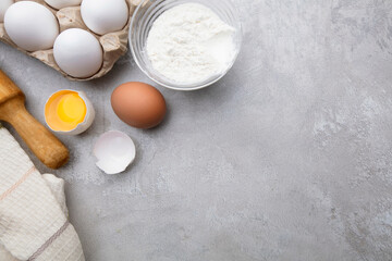 Baking cooking ingredients flour eggs rolling pin and kitchen textiles on gray concrete background. Cookie pie or cake recipe mockup