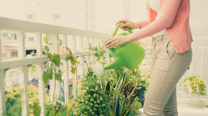 Happy Young Asian Woman housewife Watering flowers On Balcony