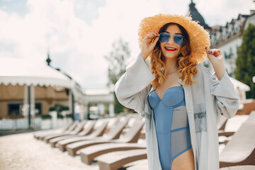 Girl near a pool. Woman in a stylish swimsuits. Lady on a summer vacation