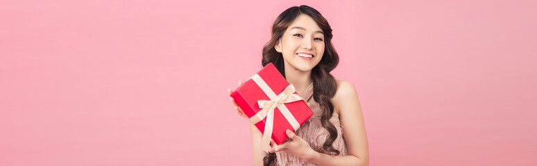 Young woman holding gift box with biege bow being excited and surprised holiday present
