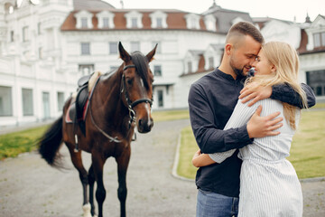 Fototapeta premium Couple in a summer rainy park. Pair standing with a horse. Girl in a white dress