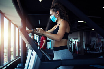 Fototapeta na wymiar Gym as source of corona virus spreading. Female training on treadmill with protective mask during covid-19 global virus pandemic. Stay safe and healthy.