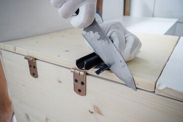 A man in white gloves cuts off the skirting board with an old knife. Repair with your own hands....