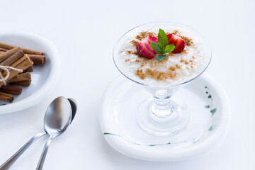 Traditional Turkish Rice Puding in stylish glass bowl wwith spoon on white background.