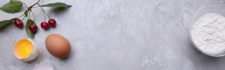 Baner of eggs berries and flour on a gray background.
