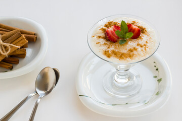 Traditional Turkish Rice Puding in stylish glass bowl on white.