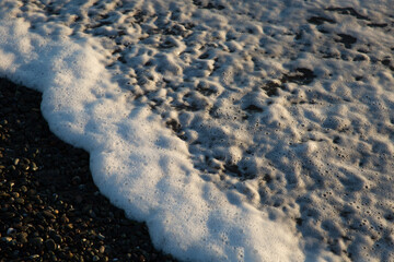closeup of ocean sea foam on dark sand