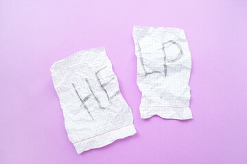 Text help on a white sheet of paper in a cage on a purple background. The concept of helping those in need.