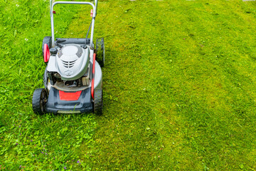 Gasoline lawn mower on the lawn with copy space