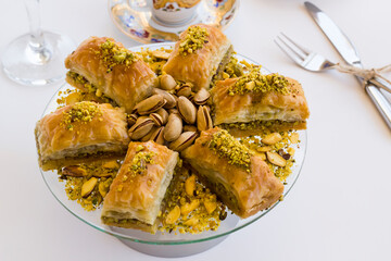 Traditional Turkish Pastry Dessert Pistachio Baklava on white with Turkish Coffee,cutlery set and a glass of water