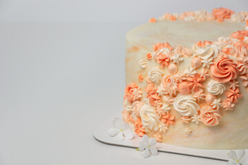 Closeup of vanila wedding cake with cream flowers decoration on light background. Event celebration consept.