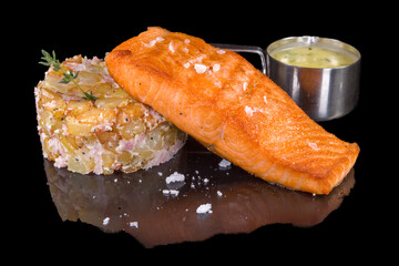 Tasty salmon fillet with potato fondant with reflection, isolated on black background