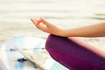 Young woman doing yoga on sup board