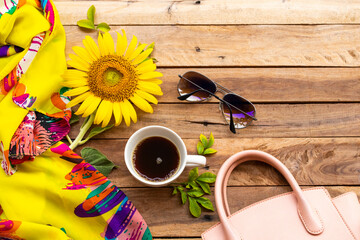 yellow flower sunflower, scarf, sunglasses, hot coffe espresso and pink hand bag accessories of lifestyle woman relax in summer season arrangement flat lay style on background wooden