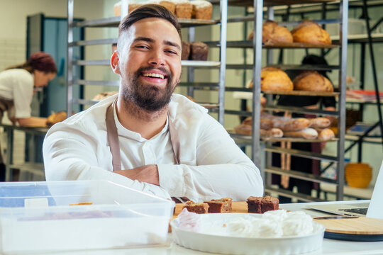 Cheerful baker delivering bread to client in store