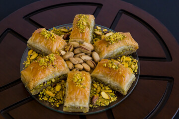 Traditional Turkish Pastry Dessert,Pistachio Baklava on the black surface with cutlery.Conceptual image of holidays.