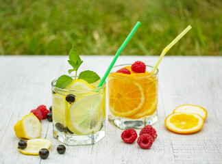 glasses with a refreshing drink of lemons and oranges with raspberries and currants
