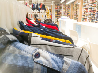 Right side view of an array of shirts hanging in a bar inside textile showroom.