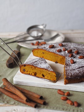 Autumn food background with healthy home cooking.Pumpkin muffin on a white wooden plate with kitchen napkin, cinnamon, powdered sugar.