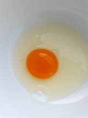 Broken raw egg in a plate.