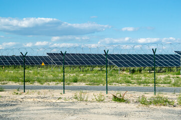 Alternative energy source, solar panels, green energy. Behind a metal fence with barbed wire.