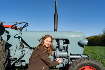 Junge Frau mit Spass an der Landwirtschaft schraubt an einem Oldtimer - Traktor. © Countrypixel