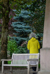 An elderly woman standing beside the pole in the park