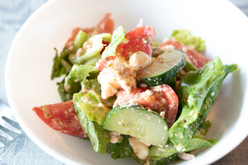 Vegetables salad with feta cheese in white bowl