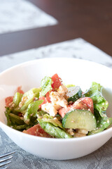 Vegetables salad with feta cheese in white bowl on table