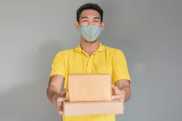 Delivery man wearing face mask in yellow uniform. newnormal lifestyle after Coronavirus pandemic.