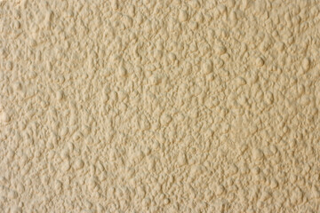 Beige wall, plaster of paris for a fur coat. Embossed porous wall surface. Decorative plaster for facade walls. Texture, background or backdrop.