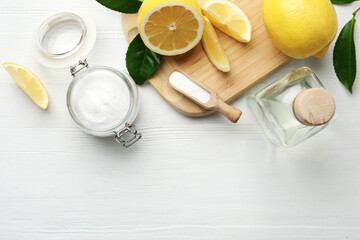 Baking soda, vinegar and cut lemons on white wooden table, flat lay. Space for text