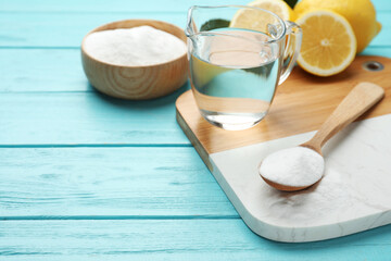 Baking soda, vinegar and cut lemons on light blue wooden table