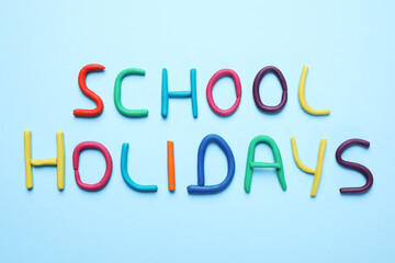Phrase School Holidays made of modeling clay on light blue background, top view