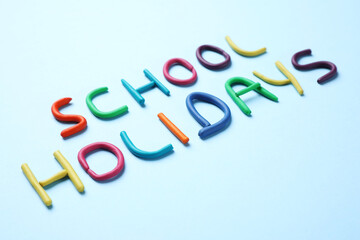 Phrase School Holidays made of modeling clay on light blue background