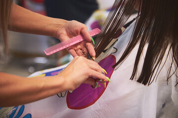 women's haircut in a Barber shop. Master universal cuts, evens the girl's hair with a comb and scissors