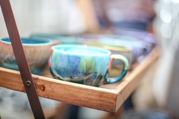 Ceramic dishes: colorful light blue cups on a wooden shelf