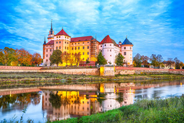 Fototapeta na wymiar Picturesque morning view of Hartenfels castle on banks of the Elbe. Dramatic sunrise