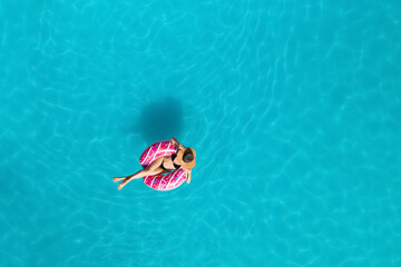 Young happy woman with inflatable ring in swimming pool, top view. Summer vacation