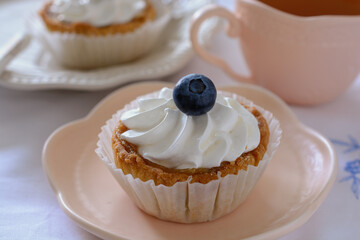 Shortcrust tartlets with whipped egg white cream on top, garnished with blueberries, close up