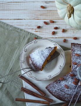 Top view.Autumn food background with healthy home cooking. Pumpkin muffin on a white wooden background with kitchen napkin, cinnamon, powdered sugar and a large pumpkin.