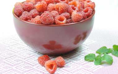 fresh raspberries in a burgundy bowl and mint leaves, healthy breakfast