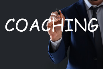 Business trainer writing word Coaching on virtual screen, closeup
