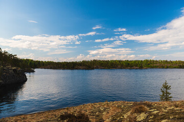Sunny day on the lake. Bright colorful photo of blue sky, trees and lake in Karelia, Russia.