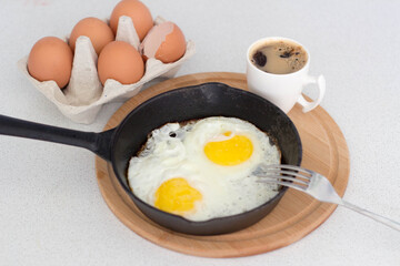 fried eggs in a small cast-iron pan Breakfast with coffee.