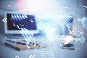 Double exposure of desktop with computer and world map hologram. International data network concept.